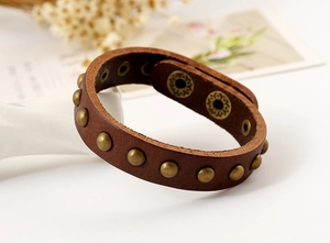 Detail of dark brown punk leather bracelet with bronze rivets and engraved snap buttons