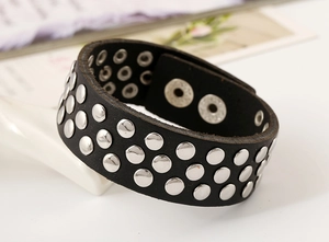Détail d'un bracelet en cuir punk noir avec trois rangées de rivets métalliques argentés
