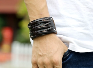 Gros plan d'un bracelet rétro en cuir tressé marron foncé avec rivets métalliques au poignet