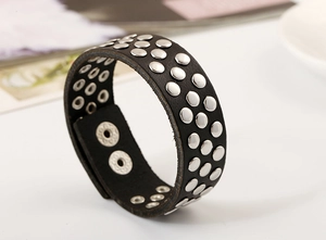 Détail du bracelet punk en cuir noir avec trois rangées de rivets argentés et boutons
