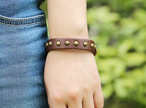 Close-up of a retro punk leather bracelet with brass studs worn in an outdoor setting