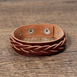 Detail of dark brown braided leather bracelet with silver metallic snap buttons on wood