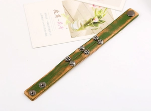 Detail of vintage green punk leather bracelet with metallic skull studs and snap button