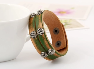 Detail of vintage green leather bracelet featuring skull studs and adjustable metal snaps