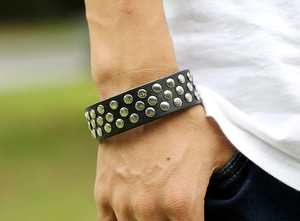 Détail du bracelet punk en cuir noir orné de trois rangées de clous métalliques argentés