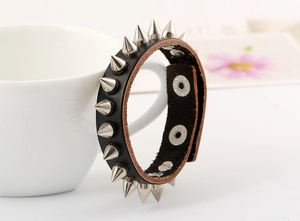 Detail view of black punk leather bracelet featuring silver metal cone spikes and snap button