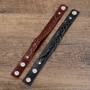 Detail of multi-layer woven leather bracelets with silver metal snaps on wooden background