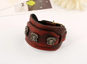Close-up of vintage red leather cuff with bronze relief ornaments and buckle detail