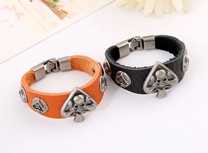 Détail de bracelets punk en cuir noir et orange avec des boucles en métal de tête de mort