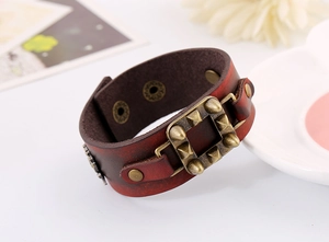 Détail du bracelet en cuir punk rouge-brun avec des clous pyramidaux en bronze et boucle