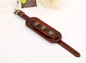 Close-up of vintage dark red wide leather bracelet with bronze metal ornaments and buckle