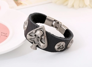 Détail d'un bracelet punk en cuir avec breloques crâne et pique en argent vieilli sur fermoir