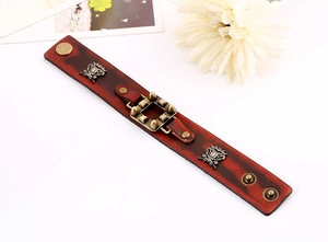 Détail d'un bracelet punk en cuir rouge foncé avec des pointes en bronze et des écussons
