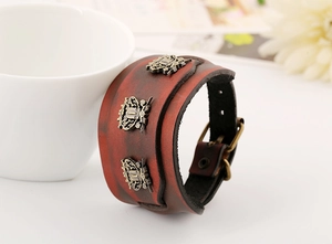 Detail of vintage wide leather bracelet with bronze relief emblems and buckle strap