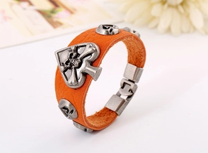 Détail macro du bracelet en cuir orange avec breloques crâne et pique de style punk