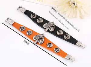 Détail de bracelets punk en cuir avec breloques tête de mort en métal en noir et orange