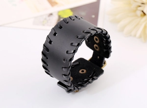Detail view of a black wide leather punk bracelet with woven edges and metal studs