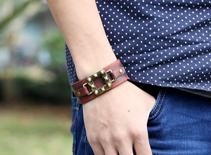 Gros plan d'un large bracelet en cuir marron de style punk avec clous en bronze au poignet