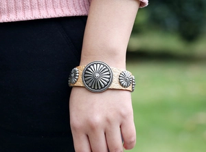Détail d'un bracelet en cuir marron vintage avec ornements métalliques floraux argentés