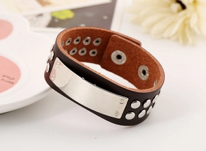 Detail of wide punk leather bracelet featuring metal studs and a brushed rectangular plate
