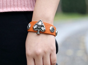 Détail d'un bracelet punk en cuir orange avec crâne vintage et breloques en métal