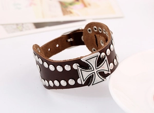 Detail of dark brown leather cuff bracelet featuring silver iron cross and metal rivets