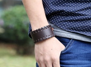 Detail of vintage wide leather bracelet with hand-stitched braided edges on wrist