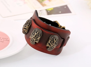Détail d'un bracelet large en cuir rétro avec trois crânes en bronze et boucle ardillon