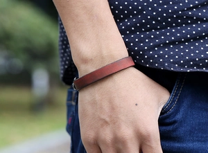 Close-up of retro reddish brown leather bracelet worn with casual lifestyle outfit
