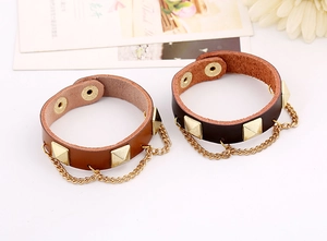 Detail view of punk leather bracelets with gold pyramid studs and hanging chains