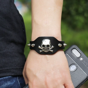 Detail of punk leather bracelet with skull centerpiece and metallic cone studs on wrist