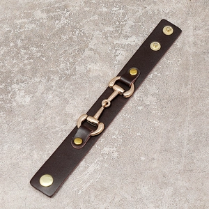 Brown leather horsebit bracelet with adjustable gold snap buttons and minimalist punk style