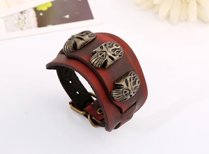 Détail du bracelet punk en cuir rouge avec des clous de crâne et boucle en bronze
