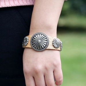 Bracelet large en cuir vintage avec charmes tournesol sur le poignet d'un modèle
