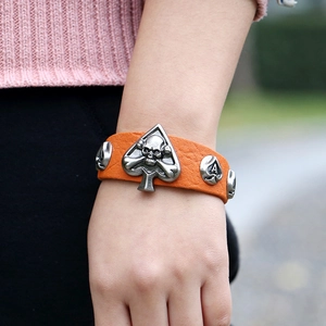 Bracelet punk en cuir orange avec boucle tête de mort en argent porté au poignet