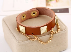 Close-up of brown leather punk bracelet featuring gold pyramid studs and fine chain detail