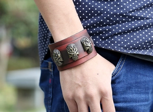 Détail d'un large bracelet punk en cuir avec trois têtes de mort dorées sur le poignet