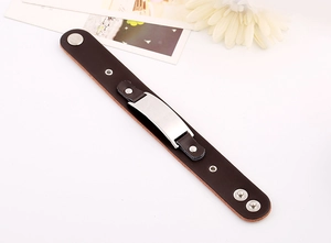 Vue détaillée du bracelet en cuir marron avec boutons-pression et plaque métallique