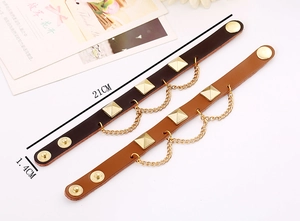 Detail of punk leather bracelets with gold pyramid studs and metal decorative chains