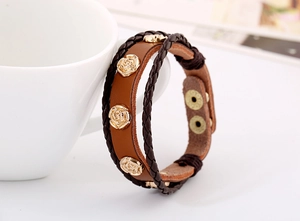 Detail of vintage brown leather bracelet with three golden rose metal charms and button
