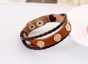 Detail of vintage brown leather bracelet with golden rose metal charms and button clasp