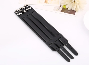 Detail of black leather punk cuff bracelet featuring three silver metal buckle straps