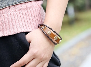 Macro view of vintage punk leather bracelet featuring gold alloy rose charms on brown cords