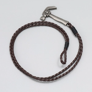Macro detail of brown braided leather cord with vintage silver hammer skull pendant