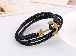 Close-up of a black multi-layer braided leather bracelet featuring a bronze anchor charm