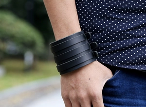 Detail of a black multi-layer punk leather bracelet worn with a casual denim outfit