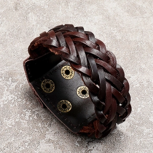 Close-up of woven brown leather bracelet with vintage bronze rivets and detailed texture