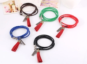 Detalle de pulsera bohemia multicapa de cuero con borlas de colores y dijes metálicos