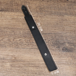 Minimalist black leather wristband with silver metal studs on a rustic wood background