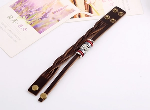 Detail of woven brown leather bracelet featuring red enamel beads and sparkling rhinestones